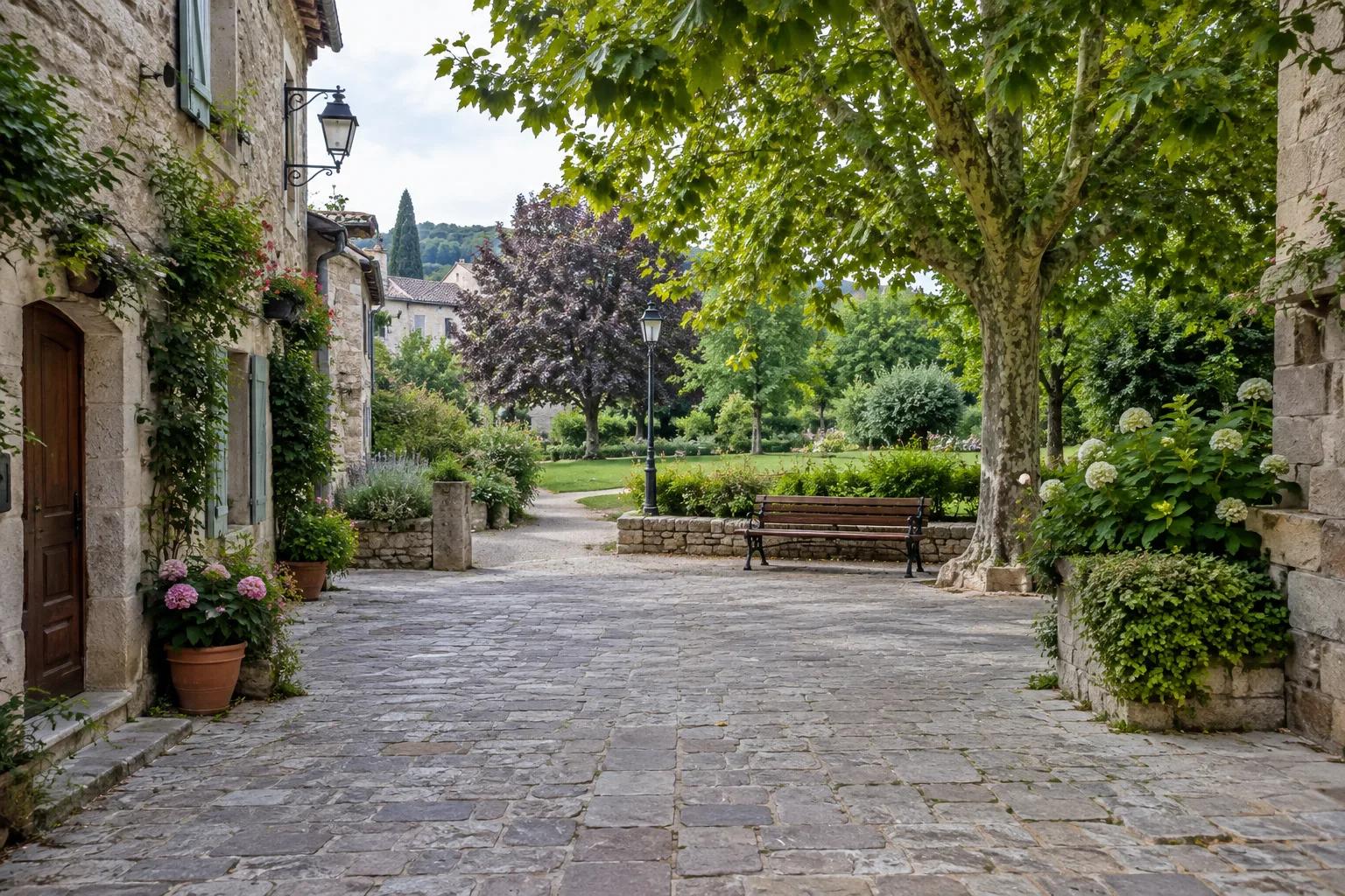 Une place ancienne mène vers un jardin public avec un banc à l’ombre.