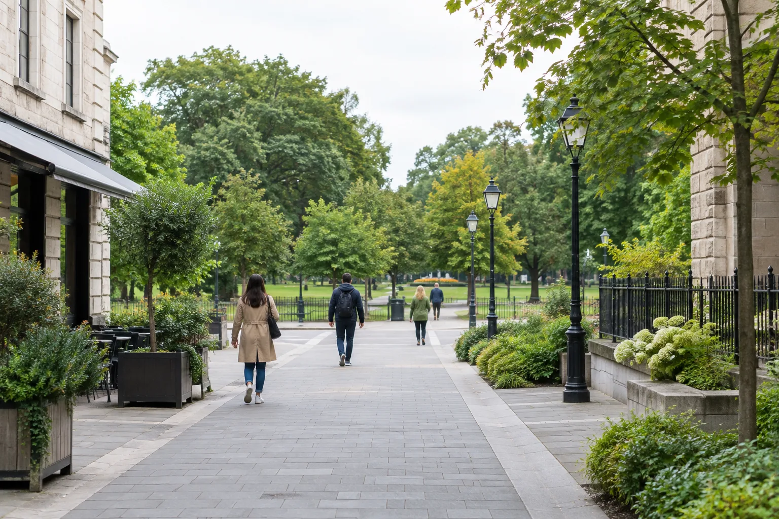 Une allée piétonne relie une place de quartier à un parc arboré.