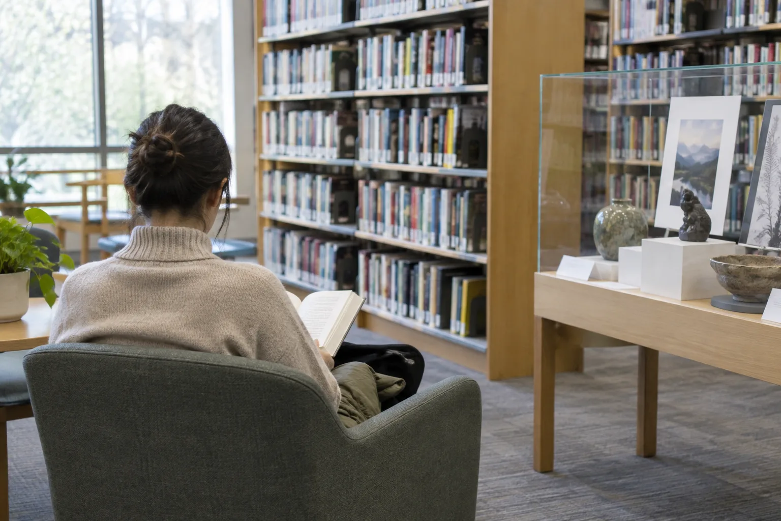 Une personne découvre les espaces de lecture et les rayonnages d’une médiathèque.